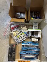 Overview photo showing boxes with various packs of batteries including button cells, AA, AAA, and a large black battery