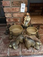 Shows entire lot arranged on brick floor including spaniel ceramic bookends, Mason-Cash dog bowls, and small brass dog figurines