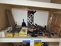 Shelf showing various tools including manual sharpeners, glass cutters, and clamps spread out with a small hand broom