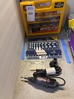Photo shows the Craftsman rotary tool, the Bosch Daredevil speed spade bit set in blister packaging, and the yellow Shop Source 16-piece Forstner drill bit case standing upright.