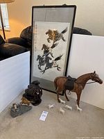 Photo showing framed Chinese horse painting, carved wood horse with leather saddle, metal gold horse on rock, porcelain horses on floor.