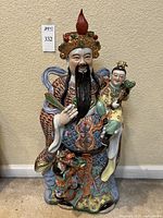 Full view of the large Fuxing porcelain figurine, showing the figure seated and holding a child with intricate colorful detailing