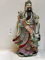 Front view of the large Chinese porcelain figurine showing the man with two children and detailed floral patterns on the robes.