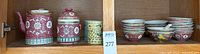 Shelf with teapot, tea caddy, yellow and blue cups, small bowls showing the lot contents