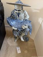 Full view of the porcelain figurine showing the man with the large koi fish and turtle.