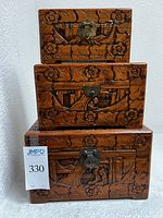 Front view of three stacked wood carved boxes showcasing floral design and metal latches