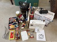 Full view of Kenmore sewing machine along with surrounding boxes and notions including pins, thread, buttons, and manual.