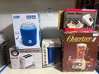 Photo showing boxed Dash Greek Yogurt Maker, boxed First Class extra-wide slot toaster, Seauglace ice bucket box, Hamilton Beach Hand Mixer box, Osterizer blender box.