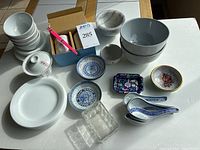 Overview of the lot showing bowls, plates, small dishes, teacup with lid, glass container, spoons and chopsticks