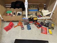 Wide shot showing all items arranged on floor including boxed bits, work aprons, Craftsman work bag, ax head and more.