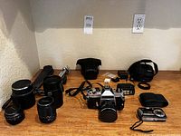 Item overview of camera, lenses, tripod and accessories on wooden surface