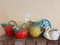 Front view of all items in the lot showing three fruit pitchers, white swan planter, and bunny Easter tray grouped on surface