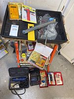 Overview of workbench with multiple hand tools and tool kits placed on shelves and the floor around it, highlighting the range of tools including hand tools, digital multimeters, and circle cutter.