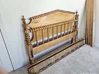 Full view of refinished wood headboard, footboard, side rails and stacked slats against wall