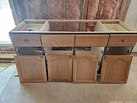 Front view of bathroom vanity showing four cabinet doors and three drawers above, all with hardware attached.