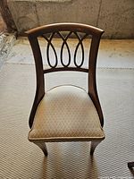 Front view of one chair showing decorative back design and upholstered seat