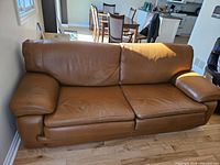 Front-angled view of caramel-brown leather sofa in living area