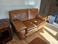 Cognac brown leather two-seat love seat showing overall condition and design.