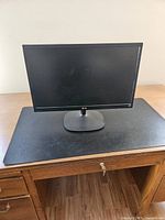 Black LG computer monitor on stand placed on a table, showing full front view.