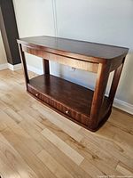 Angle view showing the side table's wood grain, drawers, and open shelf space.
