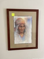 Framed original watercolor painting of elderly woman, medium brown wooden frame with matting.