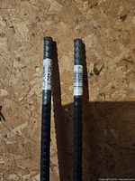 Two metal rebar rods shown with labels, placed on a wooden surface.