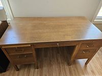 Front view of solid wood office desk showing five lockable drawers and central lock with key in place.
