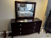 Front view of the dresser showing six drawers and silver ring pulls, placed against a wall with visible carpet beneath.
