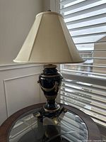 Full view of lamp on round glass-top table by window