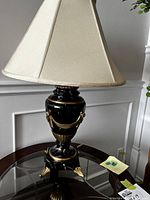 Full view of the lamp on a glass table with cream walls in background.