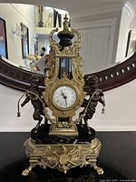 Front view of the entire mantle clock showing cherub figures, lyre-style body and marble platform