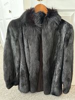 Front view of short black mink fur coat on hanger showing coat shape and fur quality