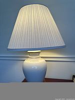 Front view of the vintage table lamp showing cream/ivory ceramic base and pleated lamp shade.