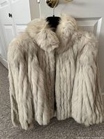 Front angled view of ivory fox fur coat showing plush collar and closure