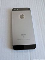 Back of Apple iPhone SE showing silver body, black top and bottom, Apple logo, and iPhone SE marking.