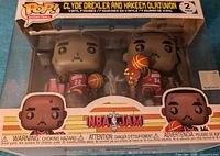 Front view of the boxed two-pack with Clyde Drexler and Hakeem Olajuwon Funko Pop figures visible through the plastic window.