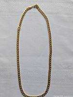 Full length view of gold tone chain necklace on white fabric background showing chain style and clasp