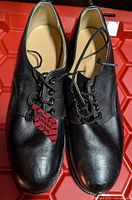 View of the tops and front of the black leather steel toe work shoes, showing lace detail and leather texture.