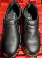 Top view of pair of black women's safety shoes showing smooth leather surface and slip-on design.