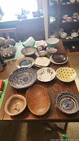 Overview of 11 assorted bowls of ceramic, pottery, and wood on table