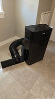 Full view of black Danby portable air conditioner with attached exhaust hose extending from the side