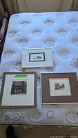 Three framed numbered prints arranged on a mattress showing size and framing style