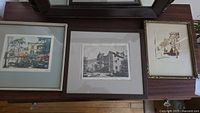 Three framed original rural scene artworks side by side on wooden surface, showing full compositions and framing style.