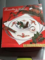 Photo of the box featuring the 2-piece glass holiday chip and dip set with poinsettia and ribbons design, showing the chip platter and dip bowl on a festive background.