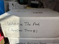Closed cardboard box with handwritten label 'Winnie The Pooh Christmas Train #1 Tigger Holiday Train'
