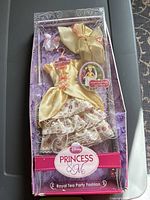 Front view of the new in box Belle doll dress and accessories including gloves and hat displayed in clear plastic packaging with floral designs and Disney Princess & Me branding.