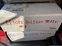 Boxes labeled 'Eeyore Holiday Train #3' and 'Piglet Christmas Train #4' indicating the figurines inside.