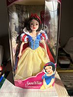 Front view of Snow White porcelain doll in original packaging showing details of doll and box design.