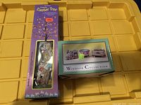 Photo showing Easter Unlimited ceramic Easter decoration in original packaging labeled Center of Easter Tree, and Windsor Collection box on yellow tray.