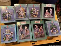Eight boxed porcelain Easter Bunny House figurines and Easter bunny figure sets by Easter Jubilee arranged on a table surface